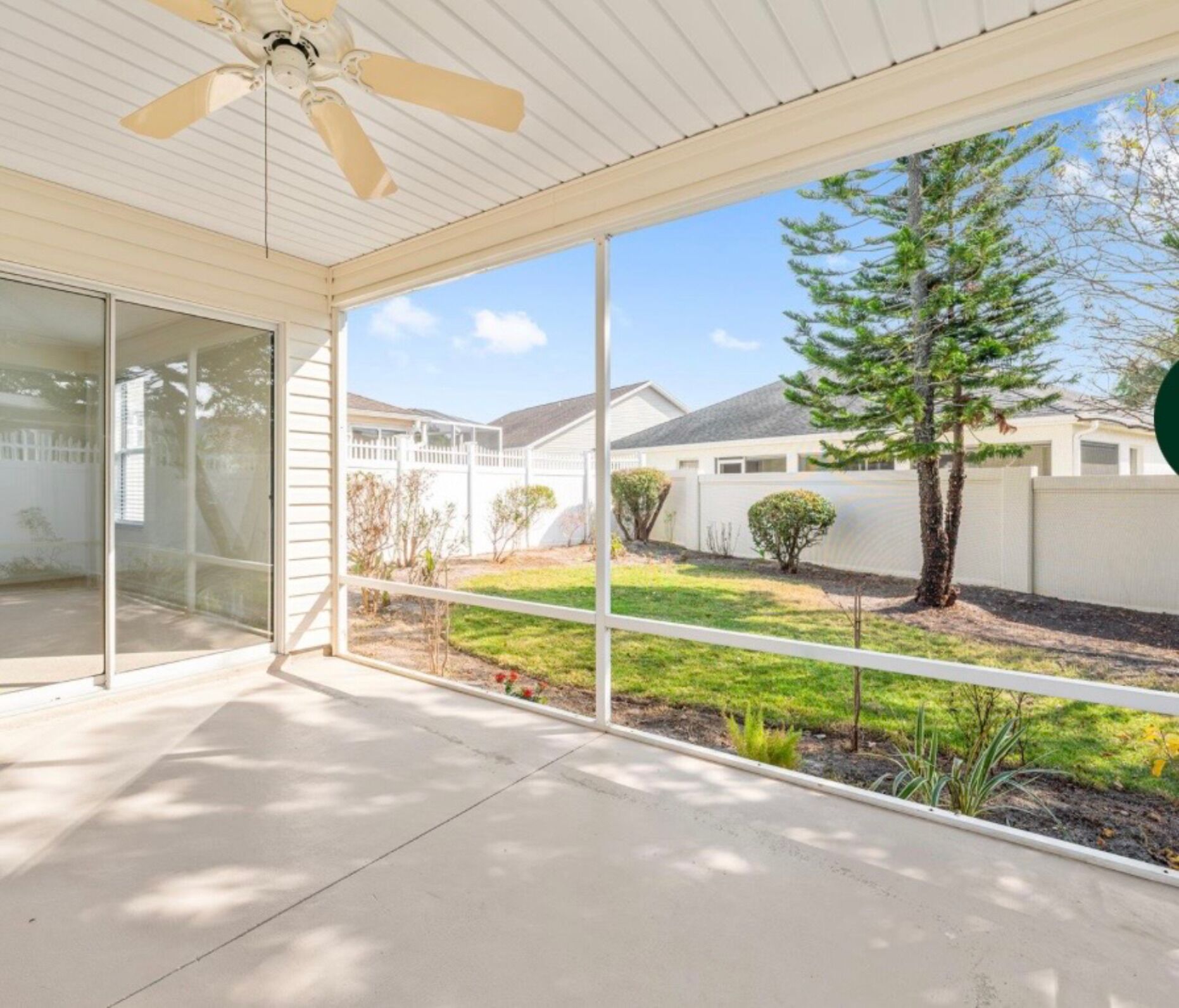A covered patio area with a ceiling fan, a glass door leading to a backyard, and a view of a residential neighborhood.