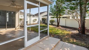 A house with a covered patio, a sliding glass door, and a small yard with trees and a fence. - The Villages FL. Courtyard, Villa House, Golf Cart, Dogs Welcome, Fenced Yard. (The Villages)