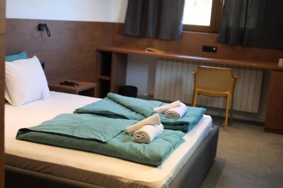 A hotel room with a bed, a desk, and a chair.