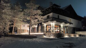A two-story building with a stone facade, large windows, and a covered outdoor seating area. - Vila Plamenac (Divčibare)