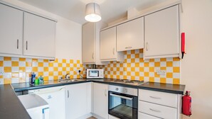 A kitchen with white cabinets, a microwave, and a red fire extinguisher. - Bright & Spacious Limerick Apt Prime Location (Limerick)
