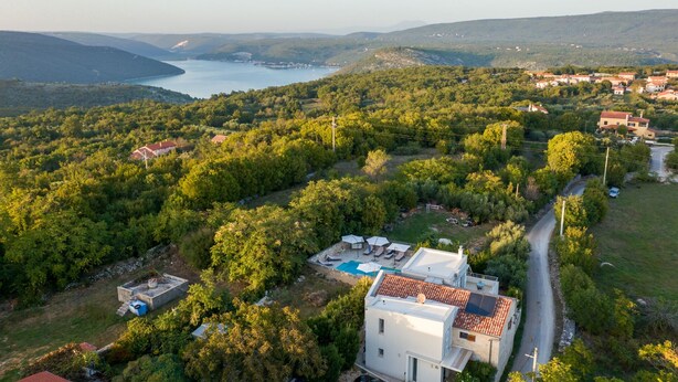 Vista aérea de una zona residencial con piscina, casas y una calle.