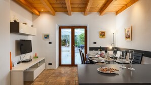Una cocina moderna con comedor, vigas de madera en el techo, televisor y vistas al exterior.