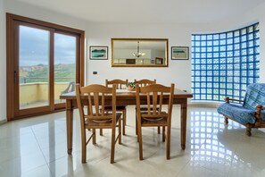 Un comedor con mesa y sillas, un espejo grande y vistas a través de una ventana con diseño de cuadrícula.