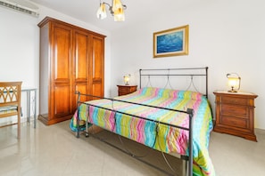 Un dormitorio con cama, armario de madera, mesitas de noche y un cuadro en la pared.