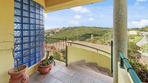 Ein Balkon mit Blick auf eine hügelige Landschaft, einem Fliesenboden und Blumentöpfen.