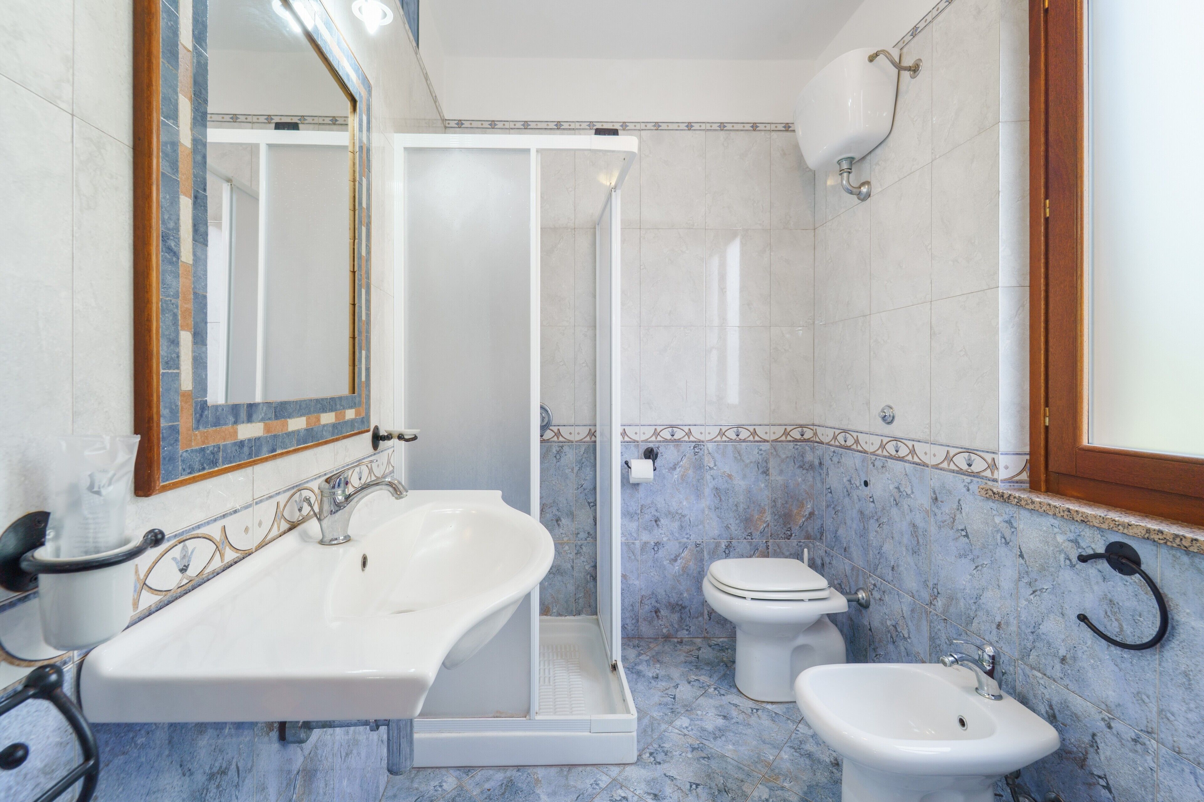 Een badkamer met douche, wastafel, toilet en bidet.