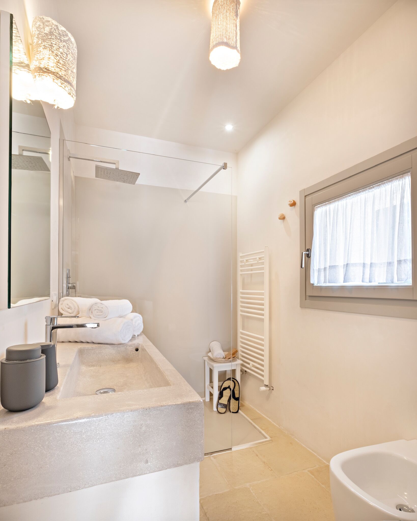 A modern bathroom with a large sink, a mirror, a shower, and a toilet.