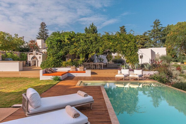 A poolside area with lounge chairs and a wooden deck. - Dimora dei Semplici (Ostuni)