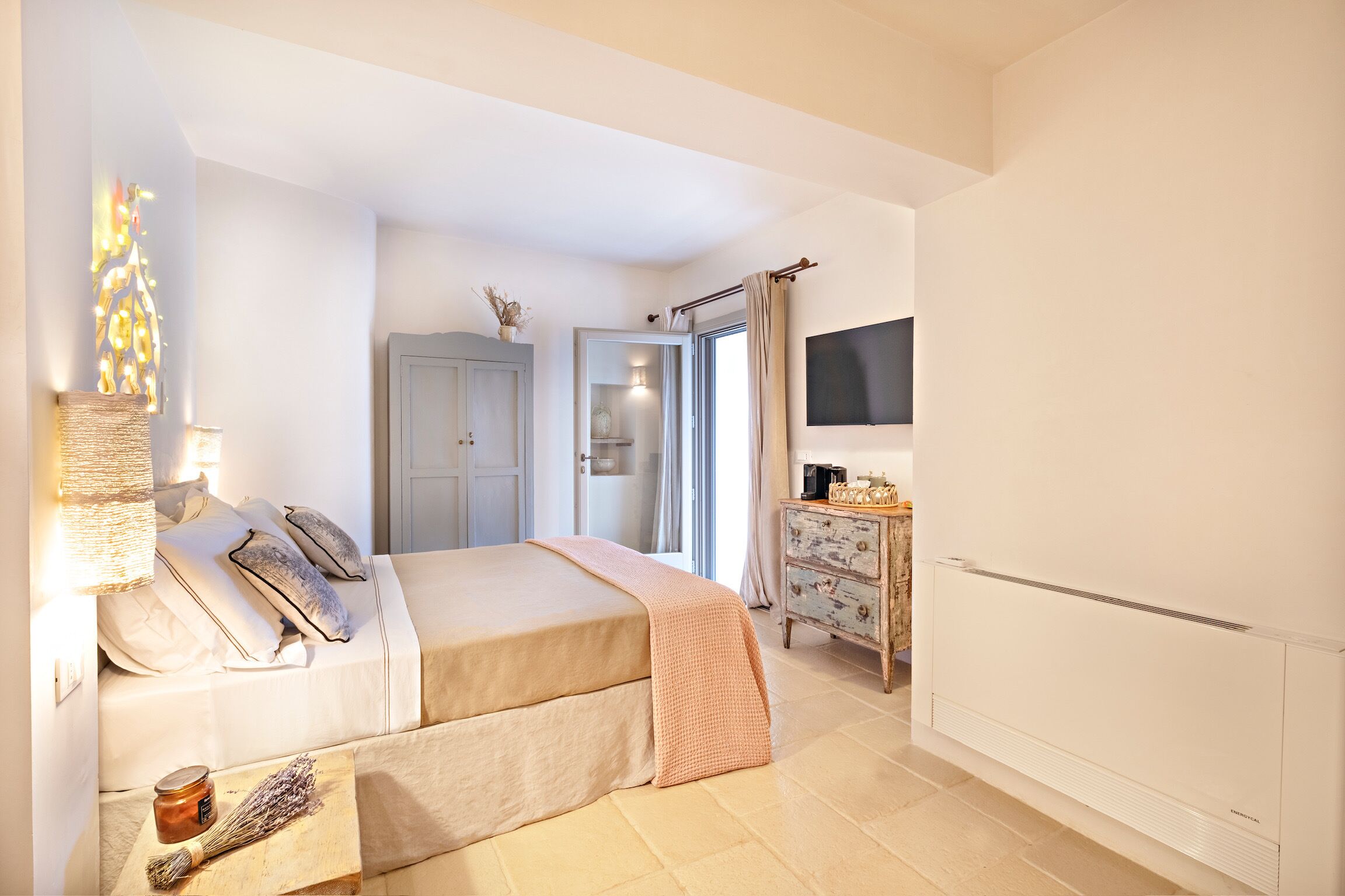 Ein Schlafzimmer mit Bett, Nachttisch, Lampe und Fernseher an der Wand.