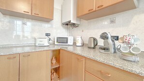 A kitchen with wooden cabinets, a microwave, a kettle, and a coffee maker. - SV - Moroni (Savona)