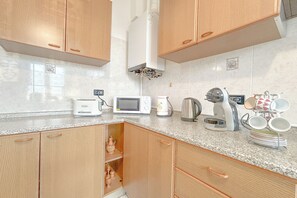 A kitchen with wooden cabinets, a microwave, a kettle, and a coffee maker. - SV - Moroni (Savona)