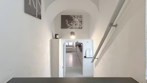 A staircase leading to a kitchen area with a white interior, a light fixture above, and a framed picture on the wall. - SV - Pia (Savona)