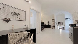 A modern, well-lit living area with a dining table, chairs, and a kitchen area in the background. - SV - Pia (Savona)