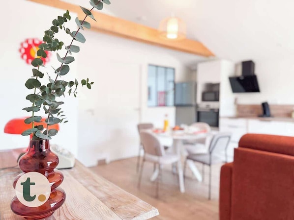 A modern kitchen with white cabinets, a red chair, and a dining table.