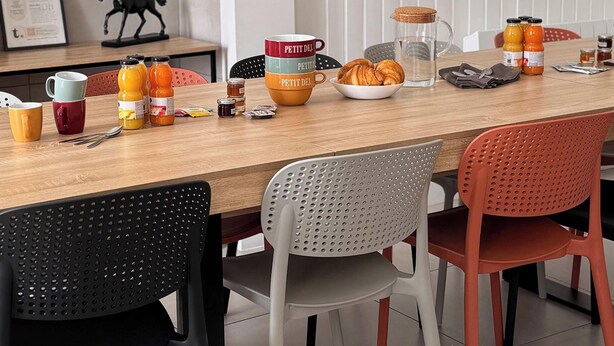 Ein Essbereich mit einem Holztisch, Stühlen, einer Karaffe und verschiedenen Frühstücksangeboten.