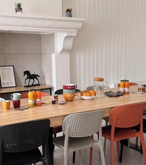 Een eethoek met een houten tafel, stoelen, een glazen kan en diverse ontbijtartikelen.