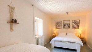 Ein Schlafzimmer mit zwei Betten, einem Wandbehang aus Makramee und drei gerahmten Bildern an der Wand.