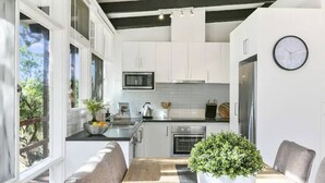 Una cocina moderna con armarios blancos, una mesa de comedor de madera y una planta en maceta.