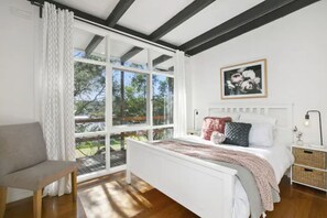 A bedroom with a large window, a bed, a bedside table, and a chair. - The Moonah Beach Shack (Rye)