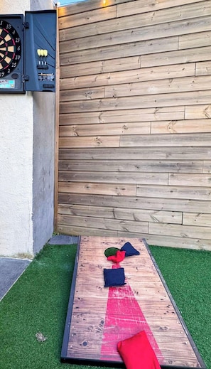 A dartboard mounted on a wall, a dartboard with a timer, and a small table with cushions. - Tranquiloue - Gite 15 personnes - 10min Puy du Fou (Saint-Mars-la-Réorthe)