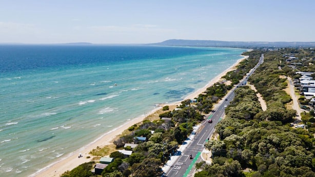 An aerial view of a coastal area with a beach, a road, and residential buildings. - Yera Coastal Homestead with Tennis Court & Spa (Rye)