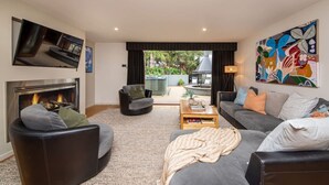 A modern living room with a fireplace, a sofa, a coffee table, and a television. - Yera Coastal Homestead with Tennis Court & Spa (Rye)