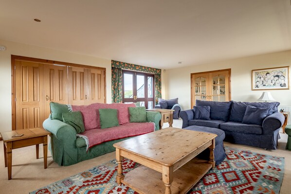 A living room with two sofas, a wooden coffee table, and a patterned rug. - Melon Park | Elie & Earlsferry (Elie)