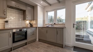 Een moderne keuken met een ingebouwde oven, een vaatwasser en een raam met uitzicht op een tuin.