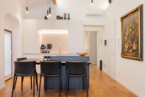 A modern kitchen with a central island, bar stools, and pendant lighting. - The Space Arena@100m (Verona)