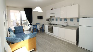 A modern kitchen with white cabinets, a microwave, and a stove. There is a dining area with a table and chairs.