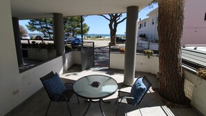 A covered outdoor seating area with a table and chairs, a view of the street, and a tree.