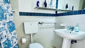 A bathroom with a toilet, sink, and a shower curtain with a nautical theme. - "La Tonnara" is a studio apartment with a sea view terrace, it is located in the central area (Castellammare del Golfo)