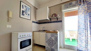 A compact kitchen with a white stove, a sink, and a patterned cabinet. - "La Tonnara" is a studio apartment with a sea view terrace, it is located in the central area (Castellammare del Golfo)