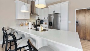 Una cocina moderna con armarios blancos, un refrigerador de acero inoxidable y una isla grande con taburetes de bar.