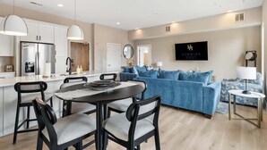 Una cocina moderna con comedor, un sofá azul y un letrero que dice 'HUMMING HOST'.