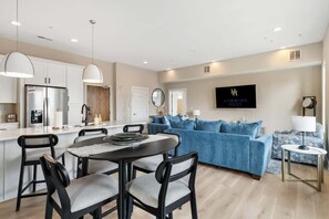 A modern kitchen with a dining area, a blue sofa, and a 'HUMMING HOST' sign. - Sun-Filled West End • Sleeps 8 + 2 Parking Spots (Nashville)