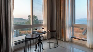 A room with large windows, a round table with two chairs, and a small stool. - ELIVAAS White House 4BHK Villa With Pool (Igatpuri)