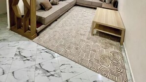 A modern living room with a sectional sofa, a patterned rug, a wooden partition, and a window with curtains. - Clima 2BR| 2 min from Tangier's Grand Stadium (Tanger)