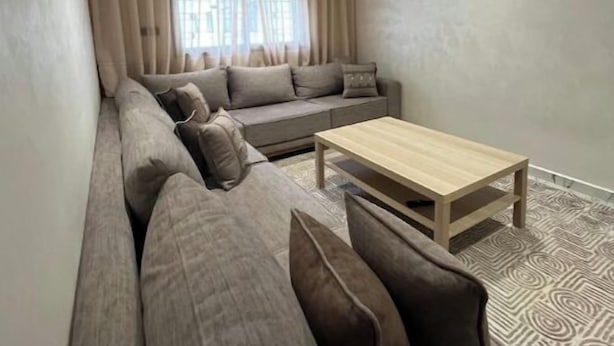A modern living room with a sofa, a coffee table, and a ceiling light fixture. - Clima 2BR| 2 min from Tangier's Grand Stadium (Tanger)