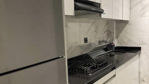 A kitchen with a modern design, featuring a stainless steel refrigerator, a black stovetop, and white cabinets. - Clima 2BR| 2 min from Tangier's Grand Stadium (Tanger)