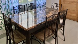 A dining area with a glass-top table and six wooden chairs. - Ferm's Residence A-spacious Apartment With Fast Wifi (Dauis)