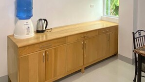 A kitchen with a wooden cabinet, a water dispenser, and a kettle. - Ferm's Residence A-spacious Apartment With Fast Wifi (Dauis)