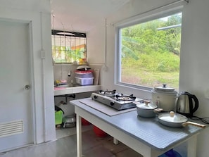 A compact kitchen with a gas stove, a sink, and a window overlooking a garden.