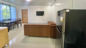 A modern kitchen with a refrigerator, a dining table with chairs, and a sofa. - Ferm's Residence A-spacious Apartment With Fast Wifi (Dauis)
