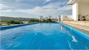 A swimming pool with a clear view of a building in the background. - Vita by Dia hotels And Homes  (Nerul)