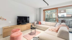 Un salón moderno con sofá, televisión y una mesita con una botella y velas.