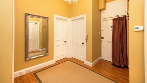 A hallway with a mirror, white doors, a chandelier, and a brown curtain. - Stylish Southside Flat Near Old Town (Edinburgh)