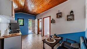 Une cuisine équipée d’une cuisinière, une table à manger avec des sets de table, un canapé et un couloir avec un plafond en bois.