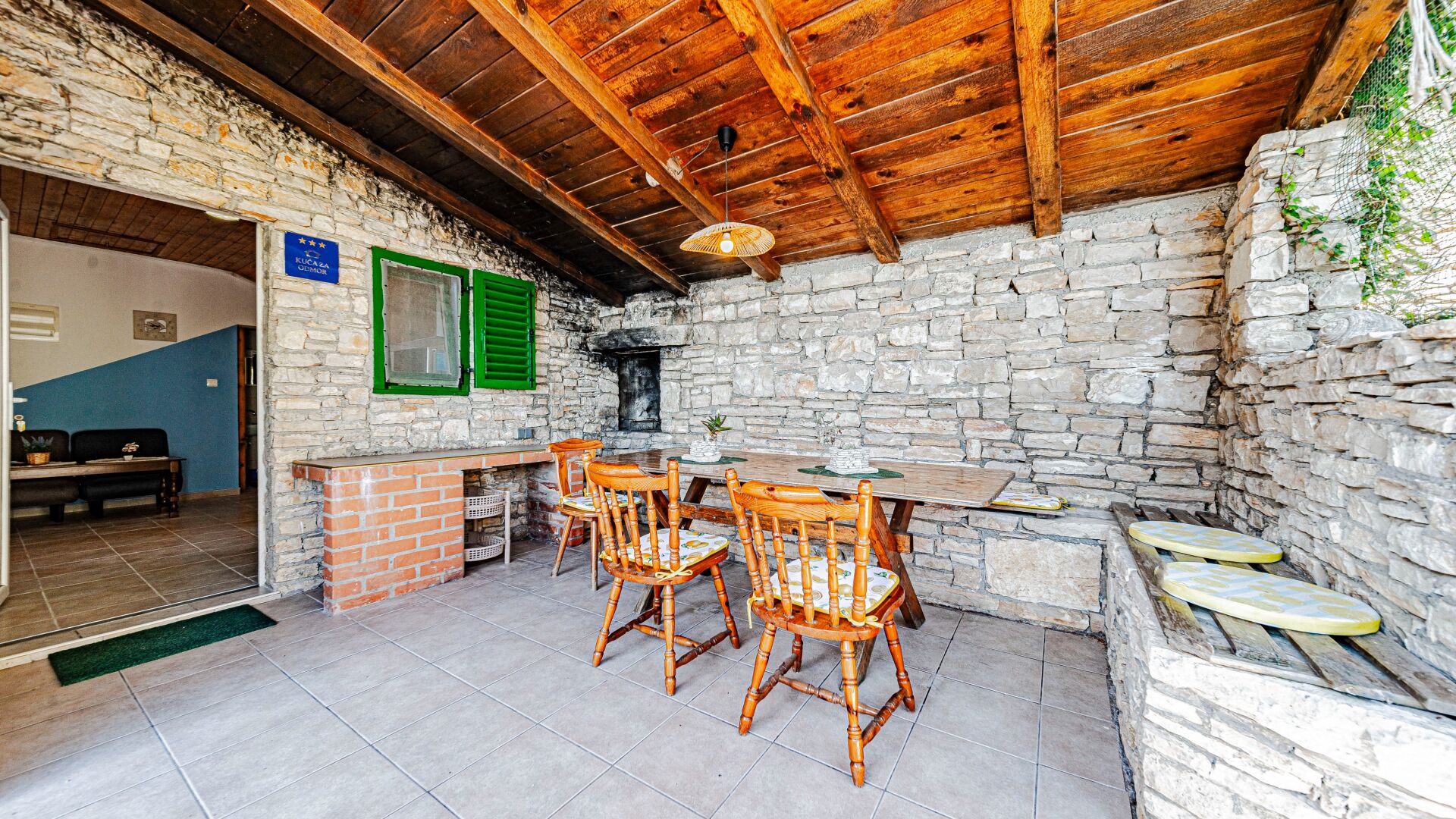 Une pièce rustique aux murs de pierre, avec un plafond en bois, un comptoir en briques et des chaises en bois.